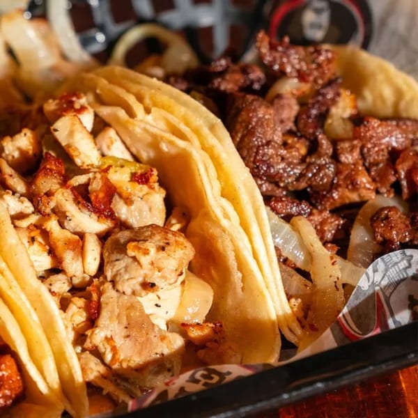 Two El Paisa Cocina Mexicana tacos, one with chicken and one with beef, both with onions.